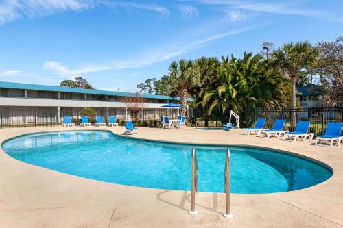 a swimming pool with blue chairs and a building at Baymont by Wyndham Daytona Beach - Intl Speedway in Daytona Beach