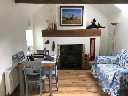 sala de estar con mesa, sofá y chimenea en An Bothán-Cosy Cottage in the Cooley Mountains en Dundalk