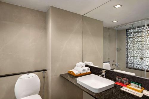 a bathroom with a toilet and a sink and a mirror at Ramada by Wyndham Jaipur North in Jaipur