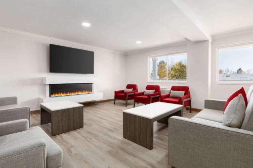 a waiting room with a fireplace and red chairs at Ramada by Wyndham Miramichi New Brunswick in Miramichi