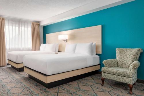 a hotel room with two beds and a chair at Ramada by Wyndham Miramichi New Brunswick in Miramichi