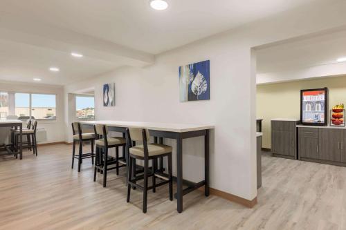 a kitchen with a bar with stools in a room at Ramada by Wyndham Miramichi New Brunswick in Miramichi