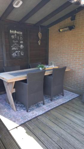 a wooden table and chairs on a rug with a table and a chalkboard at Bed & Breakfast De Schans in Makkum