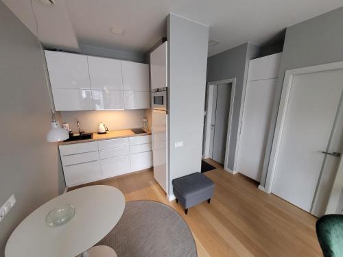 a white kitchen with a table and a chair at New Apartment,free parking in the Center in Klaipėda
