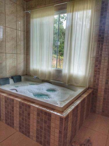 uma grande banheira com uma janela na casa de banho em Cabana Recanto do Physalis em Rio Rufino