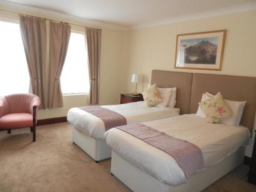 a hotel room with two beds and a chair at Morangie Hotel Tain in Tain