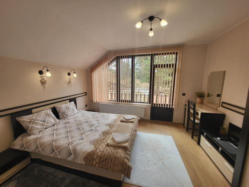 a bedroom with a bed and a desk and a window at Ваканционна къща ,,Родопски уют " in Dospat