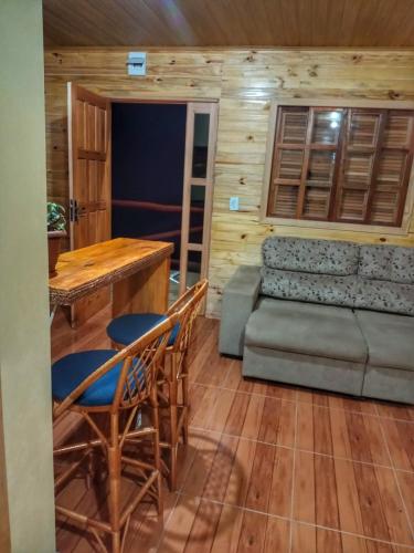 a living room with a couch and a table and chairs at Cabana Com Hidro e Lareira! Com Uma Linda Vista Para o Morro das Torres de Urupema in Rio Rufino