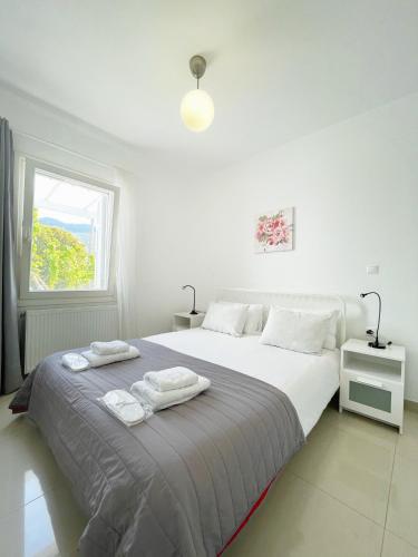 biała sypialnia z dużym łóżkiem i ręcznikami w obiekcie Bright & Cozy Flat - 2 mins to the Town w mieście Andros