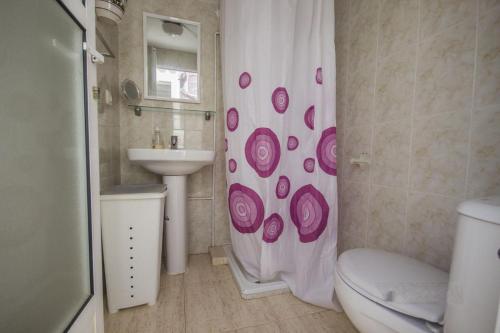 e bagno con servizi igienici, lavandino e tenda per la doccia. di Apartamento a 300m de la playa en Roquetas de Mar a Roquetas de Mar