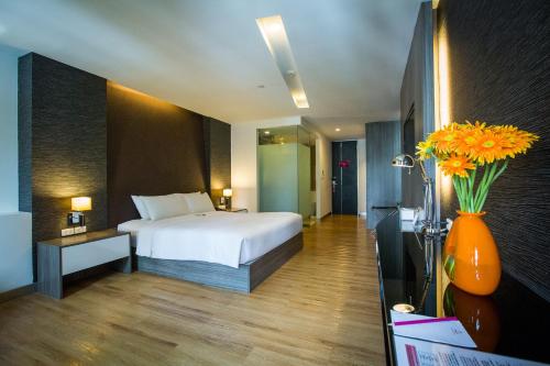 una habitación de hotel con una cama y un jarrón de flores en Trinity Silom Hotel en Bangkok