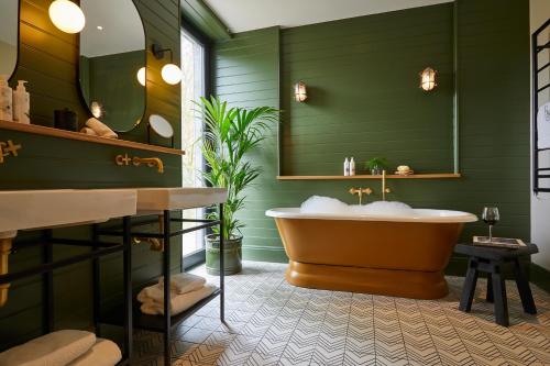 a green bathroom with a tub and a mirror at Rothay Manor Hotel in Ambleside