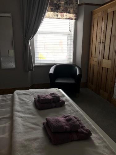 a bedroom with a bed with two pillows and a chair at Wisteria house in Plymouth