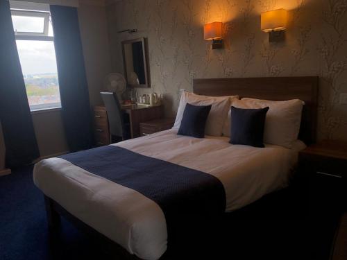 a bedroom with a large bed with blue and white pillows at The Continental Hotel, Derby in Derby