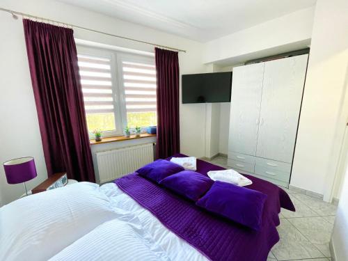 ミエンジズドロイェにあるChrobry by Baltic Homeのベッドルーム1室(紫のシーツが敷かれた大型ベッド1台付)