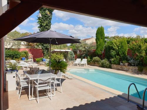 - une terrasse avec une table et un parasol à côté de la piscine dans l'établissement REDHOUSE Studio Zen, à Roques