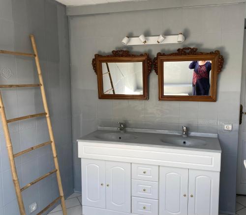 a bathroom with a white sink and two mirrors at La Maison bleue in Varzy