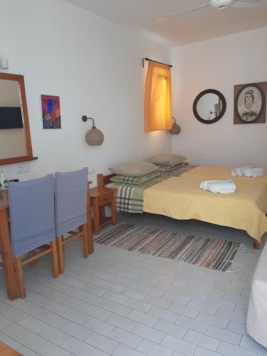 a bedroom with two beds and a table and chairs at Angela's Rooms in Mikonos