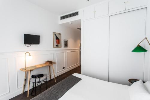 een slaapkamer met een bed en een bureau met een televisie bij Hotel Trueba in San Sebastian