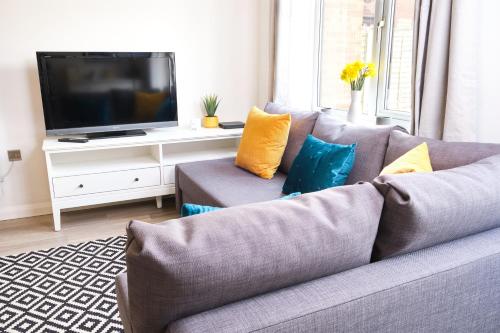a gray couch with pillows in a living room at Parkway House - Modern with great transport links in Bristol