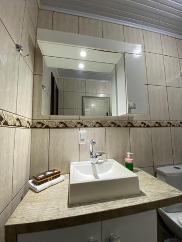 un baño con lavabo y espejo en Residenciais Maria Flor, en Gramado