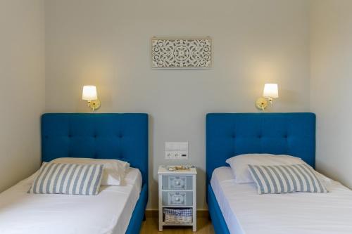 two beds in a bedroom with blue headboards at Comfeto & Mandolato Sweet Houses in Lakithra