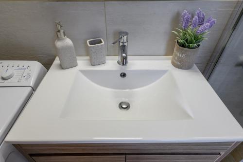 a white sink in a bathroom with purple flowers at Comfeto & Mandolato Sweet Houses in Lakithra