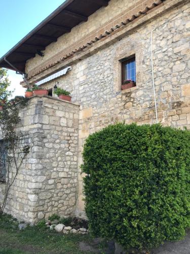 a stone building with a window and a bush at B&b La Baronata - Pescosansonesco (Pe) in Pescosansonesco