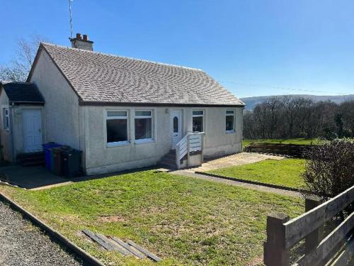 a small white house with a fence in front of it at Rural Cosy Three Bedroom Cottage in Girvan