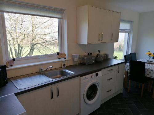 a kitchen with a sink and a washing machine at Rural Cosy Three Bedroom Cottage in Girvan