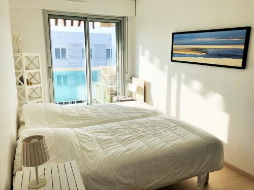 a white bedroom with a bed and a large window at JARDIN 308 Appartement avec Terrasse et Parking in Arcachon