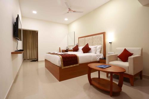 a hotel room with a bed and a chair at HOTEL BLUEMOON in Tirunelveli