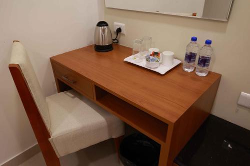 a wooden desk with two glasses and bottles of water at HOTEL BLUEMOON in Tirunelveli