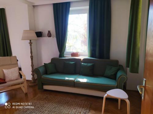 a living room with a green couch and a window at TORRE GARDEN HOME - casa singola nella città di Bolzano con giardino privato in Bolzano