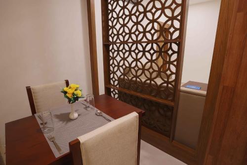 a dining room with a table and a vase of flowers at HOTEL BLUEMOON in Tirunelveli
