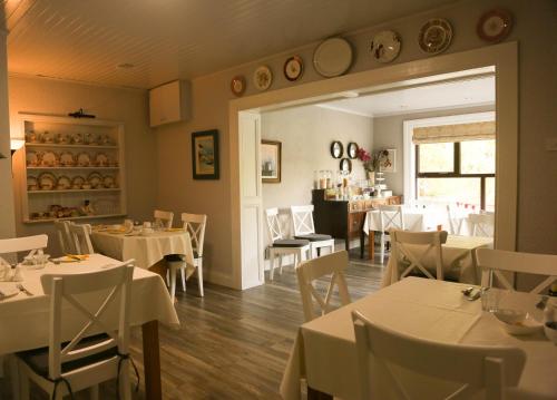 uma sala de jantar com mesas brancas e cadeiras brancas em Ben Breen House B&B em Clifden