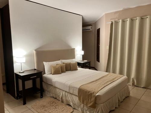 a bedroom with a large bed with two tables and two lamps at Las Arecas - rucci 61 in Puerto Iguazú