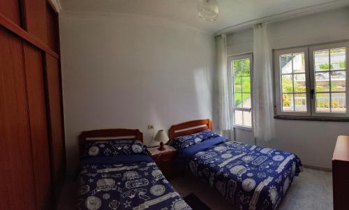a bedroom with two beds and two windows at Apartamentos Playa Monte Pindo - Morada Druida in O Pindo