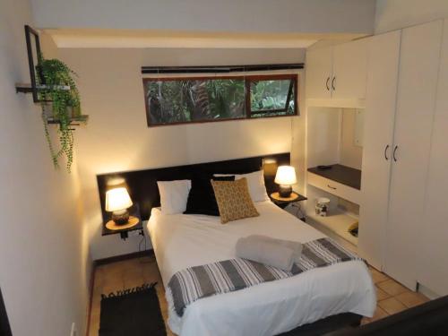 1 dormitorio con 1 cama grande y 2 lámparas en 1A @ Thatches, en Kei-mouth Village