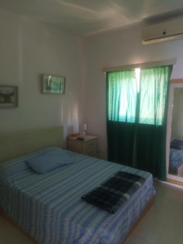 1 dormitorio con 1 cama con cortina verde y ventana en A Seafront Home away from home, en St Paul's Bay