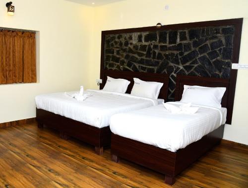 two beds in a room with white sheets at Hotel R Inn Yercaud in Yercaud
