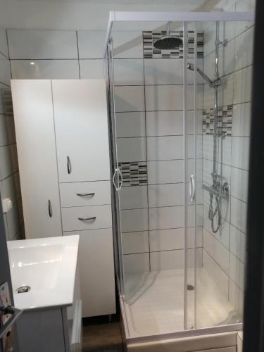 une douche avec une porte vitrée à côté d'un lavabo dans l'établissement Risoul 1850 appartement 4 personnes proches pistes., à Risoul