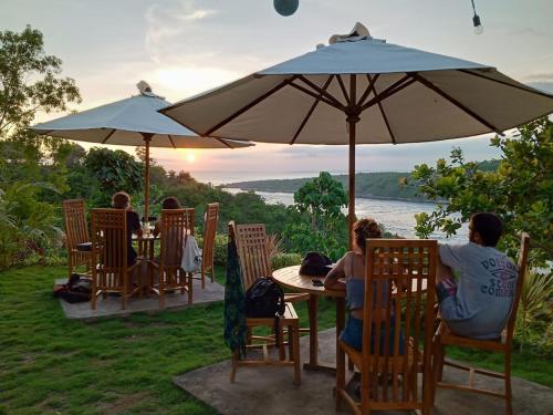 a group of people sitting at a table under an umbrella at Sakti OceanView Nusa Penida in Nusa Penida