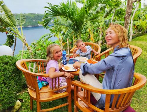 a woman and two children sitting at a table at Sakti OceanView Nusa Penida in Nusa Penida