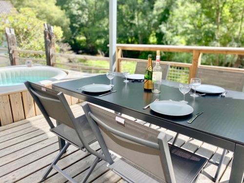 - une table avec 2 chaises, des bouteilles de vin et des verres dans l'établissement Usine du Moulin du Pont Neuf, à Trégrom