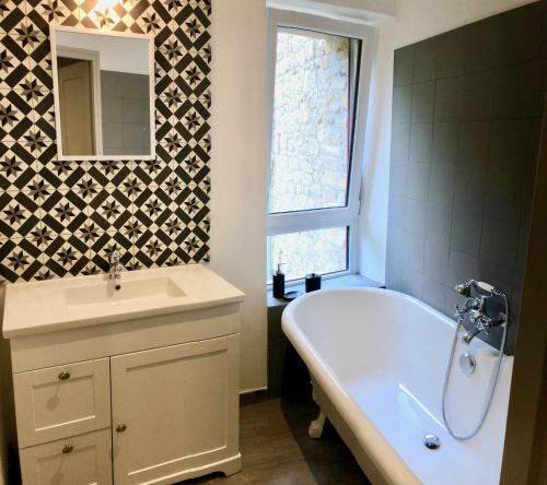 a bathroom with a tub and a sink and a mirror at Usine du Moulin du Pont Neuf in Trégrom
