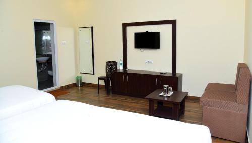 a living room with a bed and a couch and a tv at Hotel R Inn Yercaud in Yercaud