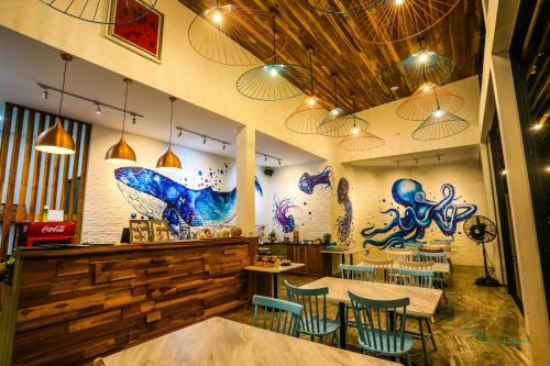 uma sala de jantar com mesas e cadeiras e uma parede com pinturas em Tique Series Boutique Resort (SHA Extra Plus) em Ban Hat Lek