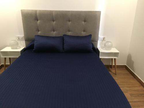 コニル・デ・ラ・フロンテーラにあるLas Casitasのベッド1台(青い掛け布団、テーブル2台付)