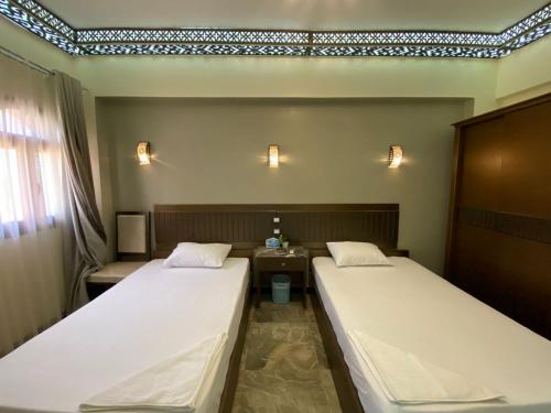 a room with two beds and a table with a window at Shabana House in Dahab